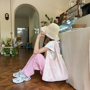 Detailed shot of floral canvas tote bag with white lace trim and straw hat in a cafe