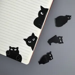 Close-up detail of cute black cat magnetic bookmarks clipped to a notebook page