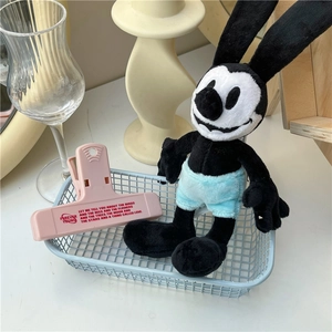 Close-up of blue wire storage basket with pink clip and black plush rabbit on a desk