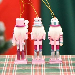 Three pink candy-themed Christmas nutcracker doll ornaments with gold hanging strings