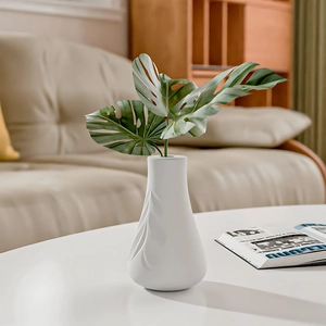 Minimalist white ceramic vase with streamline texture and faux Monstera leaves for home decor