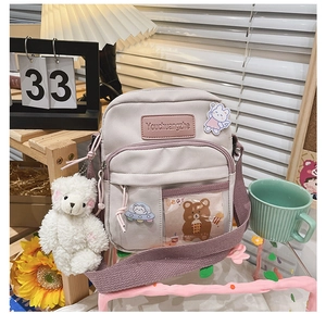 Détail du sac bandoulière en toile violet clair avec pendentif ours et compartiments