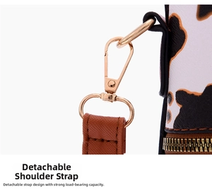 Detail of cow print handbag featuring brown leather strap and golden swivel snap hook