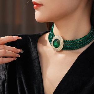 Close-up of green beaded necklace with gold emerald pendant worn by a model