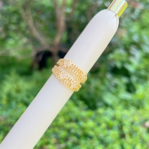 18K gold plated mesh ring with zircon stones on white stand with green background