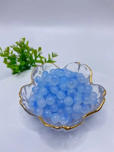 Close-up of 8mm translucent blue glass beads for DIY jewelry in a gold-rimmed bowl