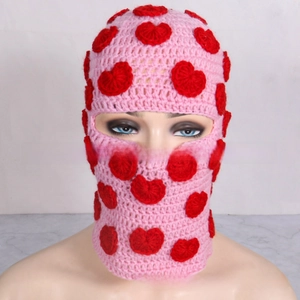 Macro shot of handmade pink knitted balaclava with red heart patterns and soft texture