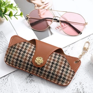 Brown leather and houndstooth glasses case with gold floral buckle and pink sunglasses