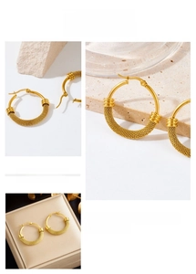 Macro detail of gold-plated twisted mesh texture on geometric titanium hoop earrings