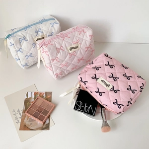 Close-up of quilted bow-patterned makeup bags with zipper and brand label details