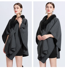 Detail of dark grey knit cape with black faux fur collar and pompom hem details