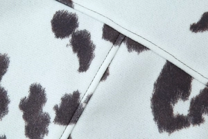 Gros plan du tissu à motif vache noir et blanc avec coutures détaillées sur la veste