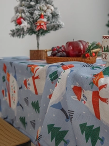 Close-up of blue cotton linen Christmas tablecloth with Santa and tree patterns