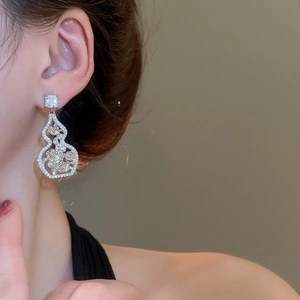 Detail of silver gourd earrings with hollow flower patterns and zircon inlays on model