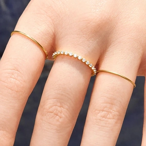 Macro detail of a 3-piece minimalist gold ring set featuring a sparkling zircon band