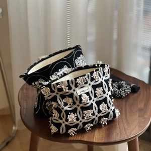 Gros plan sur une trousse en toile noire avec broderies bohèmes blanches et fermeture éclair