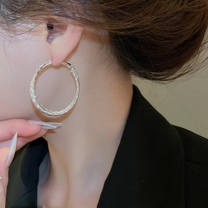 Detail view of large silver circle earrings with a stylish spiral textured metal surface