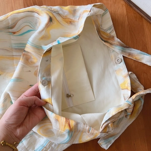 Detail of the magnetic snap closure and zippered inner pocket on the marble printed tote
