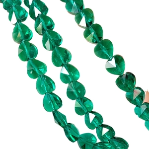 Macro shot of faceted emerald green heart-shaped crystal glass beads for jewelry making