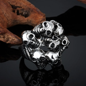Macro shot of punk style stainless steel ring with multi-skull relief on black surface
