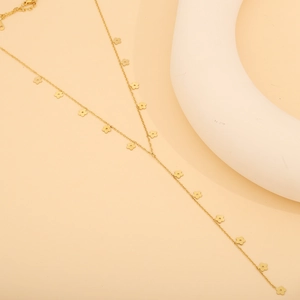Détail d'un collier doré avec pendentifs fleurs sur fond courbé minimaliste