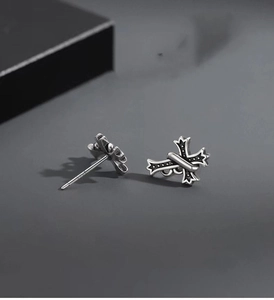 Macro detail of 925 silver gothic cross stud earring with dagger wrap on dark background
