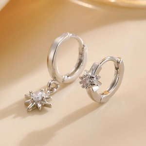 Macro shot of silver hoop earring featuring a star pendant with clear cubic zirconia stones