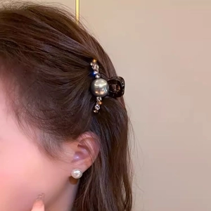Close-up of a small hair claw clip with grey pearl and rhinestones on a female model