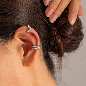Close-up of a silver C-shaped stainless steel ear cuff worn on model's ear