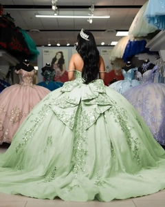 Detail of light green ball gown featuring a large layered back bow and sequin lace embroidery