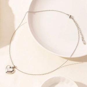 Macro detail of silver heart pendant necklace with polished finish and lobster clasp