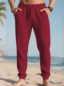 Detail of dark red waffle knit jogger pants featuring drawstring waist and textured fabric
