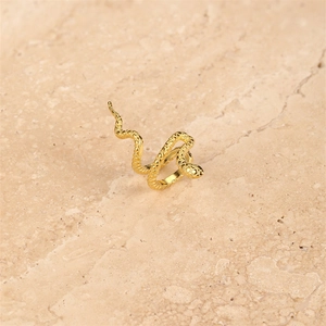 Macro view of gold snake-shaped ear cuff with detailed scale texture on stone background