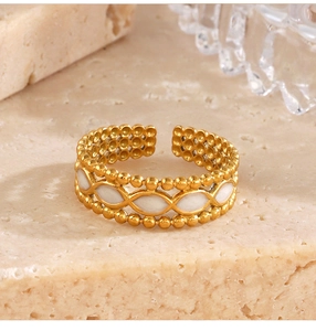 Macro detail of gold-plated open ring with white enamel ovals and beaded edges