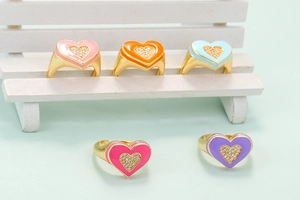 Detail of colorful enamel heart rings with pave-set zircon crystals on golden metal