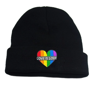 Black knit beanie with Love Is Love rainbow heart embroidery on a white background