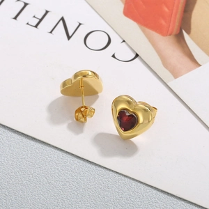 Detailed close-up of golden heart studs with red crystal and secure butterfly backings