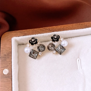 Macro detail of French style earrings with black flowers, grey crystals and white pearls