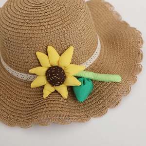 Close-up of children's straw hat featuring a decorative fabric sunflower and lace trim.