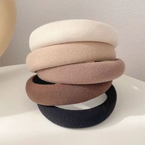 Close-up of five thick sponge headbands in neutral tones with soft fabric texture