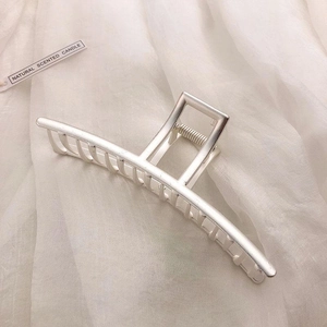 Detail of a large silver matte metal hair claw clip on soft textured fabric background