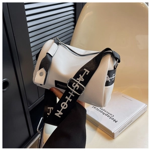 Gros plan d'un sac cylindrique blanc en cuir litchi avec large bandoulière mode