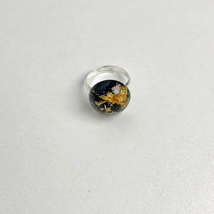 Macro detail of black resin heart ring with gold foil flakes on adjustable silver band