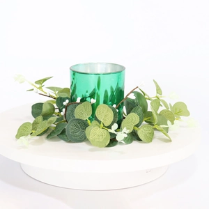 Detail of candle holder with green eucalyptus wreath and white berries on white stand