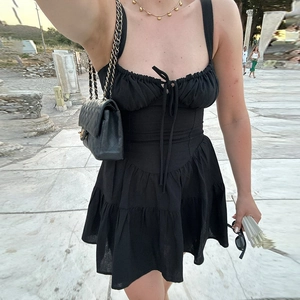 Détail d'une robe noire cintrée à la taille avec plis et texture d'aspect lin