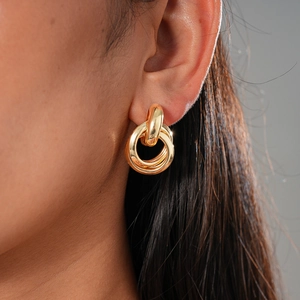 Close-up of interlocking gold triple hoop earrings worn on ear with minimalist style