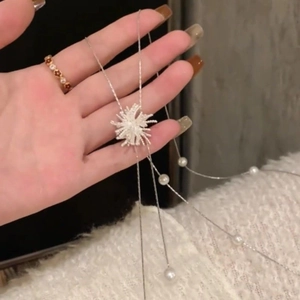Gros plan du collier à pampilles argentées avec pendentif étoile et perles blanches élégantes