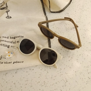 Flat lay of retro round silicone baby sunglasses in cream and olive green colors
