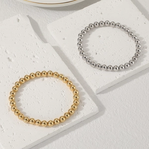 Dettaglio di bracciali con perline elastiche in oro e argento su base di pietra
