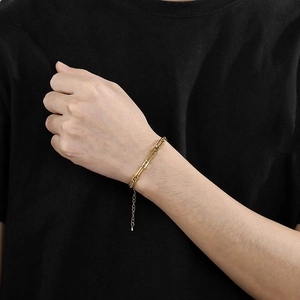 Close-up of a gold titanium hollow chain bracelet worn on a wrist against black background